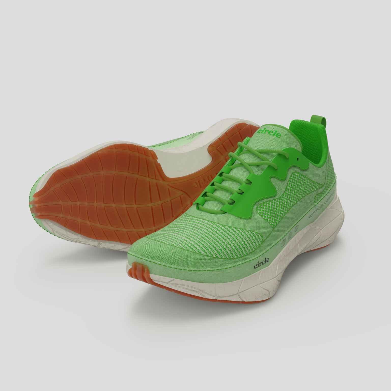 A pair of bright green running shoes with white midsoles and orange outsoles. One shoe stands upright while the other is tilted to display the sole.